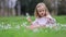 Cute preschooler girl in pink tutu skirt sitting in the grass with many snowdrop flowers