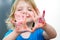 Cute preschooler girl with smile showing colored hands. Selective focus on palms