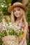 Cute preteen girl in straw hat with basket of wildflowers in green country garden