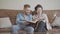 Cute pretty granny and adult grandson sitting at home on the brown leather sofa watching old photos in the big photo