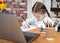 Cute pretty young girl doing complex maths writing calculations at home school with computer laptop and calculator on colourful