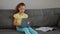 Cute primary school child girl studying with laptop at home, sit on sofa