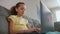 Cute primary school child girl studying with laptop at home, sit on sofa