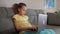 Cute primary school child girl studying with laptop at home, sit on sofa