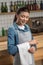 Cute professional waitress looking at the towel on her arm and smiling