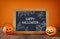 Cute pumpkins next to blackboard on wooden table