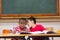 Cute pupils writing at desk in classroom