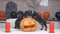 Cute puppy with bow tie made pumpkin jack-o-lantern for Halloween party, adult dachshund dog jumps on chair to check
