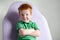 Cute red haired freckled little boy in green t-shirt waiting for doctor in medical office