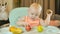 Cute red-haired girl in a high chair tastes fruits. Adorable child tasting fruits. Children\'s breakfast with fresh