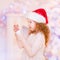 Cute red-haired little girl wearing Santa Claus hat