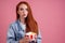 Cute red long foxy haired ginger woman holding packaging cardboard box bucket with french fries and eating chicken