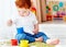 Cute redhead baby boy developing his fine motility skills by playing with green peas at home