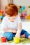 Cute redhead baby boy developing his fine motility skills by playing with green peas at home