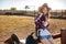 Cute redhead cowgirl sitting and resting on the ranch fence