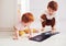 Cute redhead siblings having fun, drawing on chalk board at home