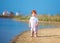 Cute redhead toddler baby boy walking at lake coast in the summer morning