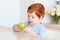 Cute redhead toddler baby eating tasty green apple