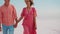 cute romantic adult couple in pink wear walking at white desert holding hands