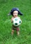 Cute Russian toddler boy in a ushanka hat is holding a soccer or football ball in his hands. Russian football concept