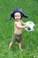 Cute Russian toddler boy in a ushanka hat is holding a soccer or football ball in his hands. Russian football concept