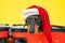 Cute sad dachshund in Santa costume and hat is lying in empty open suitcase, packed for Christmas vacation, so that
