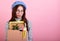 Cute sad lady in a stylish beret hat, with a cardboard box in her hands on a pink background