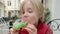 Cute school age boy eating funny colorful donut in a street cafe while walking in the city center.