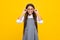 Cute school girl wearing glasses on yellow studio background, smart clever schooler girl in eyeglasses. Nerd student