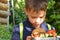 Cute schoolboy eating outdoors the school from plastick lunch boxe. Healthy school breakfast for child. Food for lunch