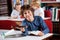 Cute Schoolboy Giving Book While Sitting At Table