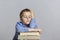 Cute schoolboy sleeps on a stack of books. Close-up. Gray background