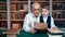 Cute schooler boy and 70s grandfather reading letter together doing homework at public retro library