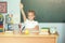 Cute schoolgirl pupil raising hand in classroom