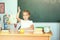 Cute schoolgirl pupil raising hand in classroom