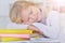 Cute schoolgirl sleeping on table after doing homework at home