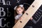 Cute schoolgirl standing before the chalkboard as a background holding the huge ruler diagonally