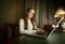 Cute schoolgirl in white shirt doing homework at laptop in dark