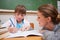 Cute schoolgirl writing a while her teacher is talking