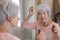 A cute senior woman in her sixties is applying drops on her scalp