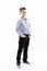 Cute serious boy a schoolboy of 8 years in a blue shirt and trousers stands holding his hands in his pockets. Full height. White