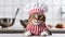 Cute serious gray striped cat in white-red striped chef\\\'s hat on gray kitchen background. Cat in the form of cook.