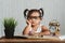Cute serious looking little asian toddler wearing eyeglasses reading a book on a table