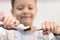 A cute seven year old boy in pajamas with a bamboo toothbrush brushes his teeth before going to bed at home in the bathroom.