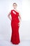 A cute short hair plus size girl with a curvy figure stands in a red long tight sequin dress with a teardrop neckline on her chest