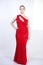 A cute short hair plus size girl with a curvy figure stands in a red long tight sequin dress with a teardrop neckline on her chest