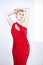 A cute short hair plus size girl with a curvy figure stands in a red long tight sequin dress with a teardrop neckline on her chest