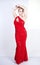 A cute short hair plus size girl with a curvy figure stands in a red long tight sequin dress with a teardrop neckline on her chest