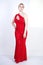 A cute short hair plus size girl with a curvy figure stands in a red long tight sequin dress with a teardrop neckline on her chest