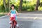 Cute short haired Asian kid girl aged 4 to 6 years riding a red bicycle in a park. Children`s outdoor cycling is a fun learning